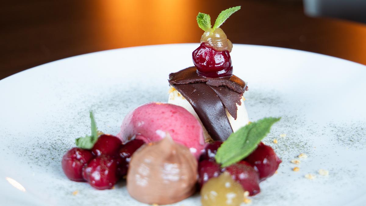 Dessert aus Schokolade, Kirschen und Beerensorbet auf weißem Teller