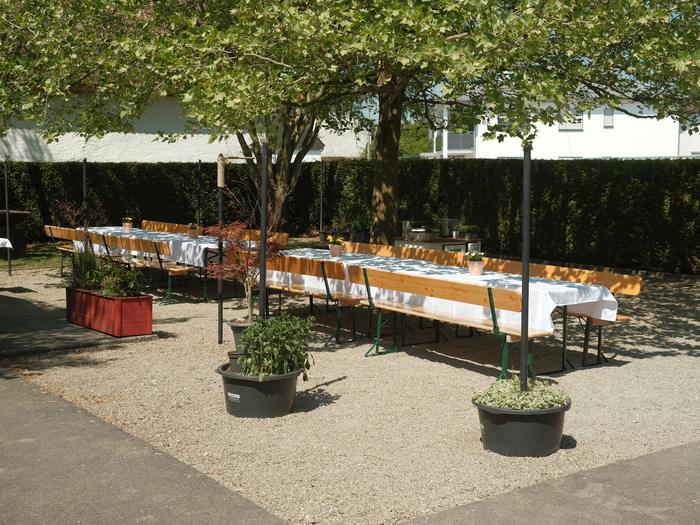 Lange weiß gedeckte Tafeln im Hof, bereit für eine Feier