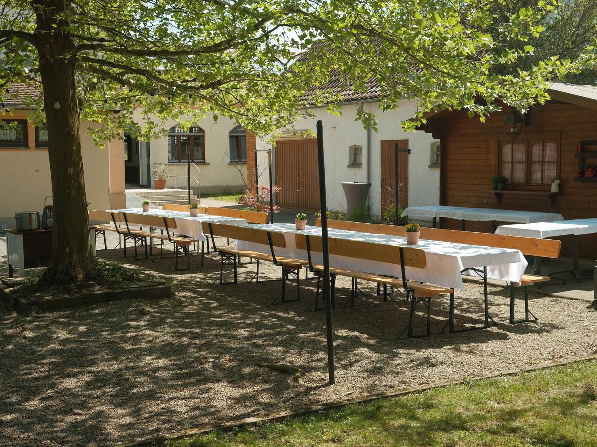 Der Hof des EssEck mit langen gedeckten Tafeln unter einer alten Platane